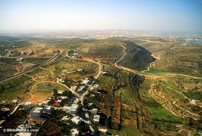 View from airplane of green hills and valleys partially-developed with roads and modern buildings