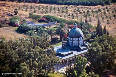 View from an airplane of a domed octagonal building with a square colonnaded area adjoining it on one side, with nearby trees and brown fields